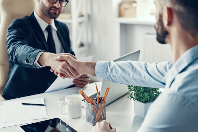 Image of two employees in an office shaking hands.